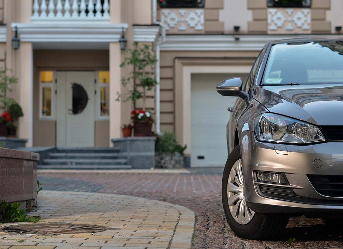 Home and Auto Insurance (Bundled) - Close-up View of a Luxury Car Parked in Front of a Large Modern Home Blurred in the Distance