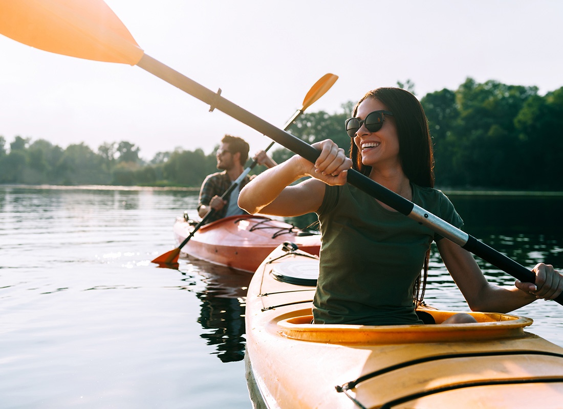 Employee Benefits - View of a Cheerful Young Couple Kayaking Together on a River on a Sunny Summer Day