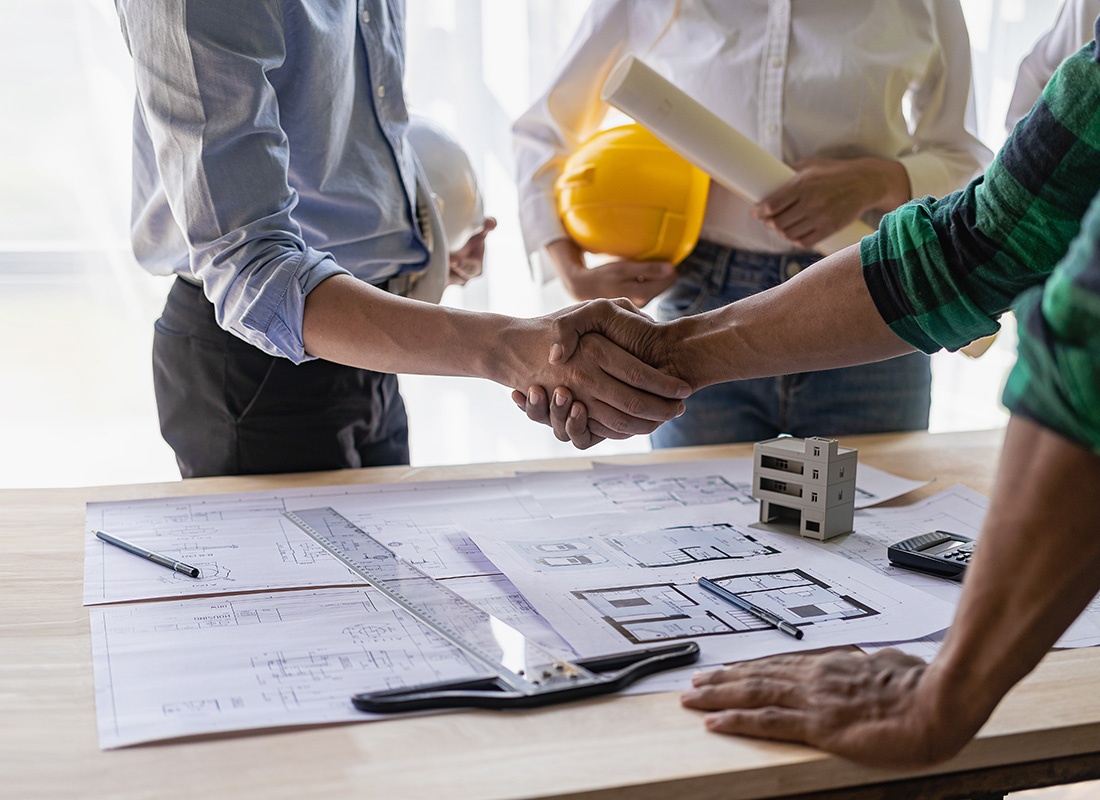 Insurance by Industry - Closeup View of Two Businessmen Shaking Hands with a Contractor During a Business Meeting with Blueprints on the Table