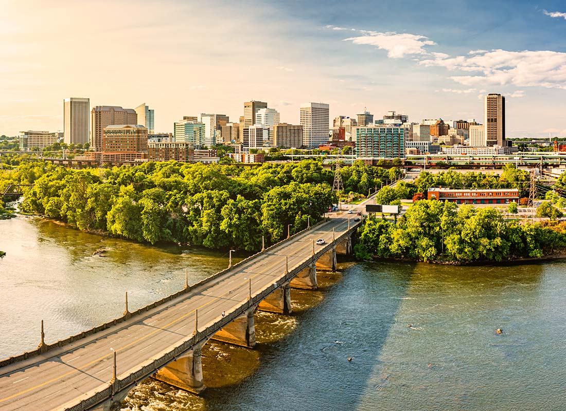 We Are Independent - Aerial View of a Bridge Across the River Leading into Downtown Richmond Virginia Surrounded by Green Foliage
